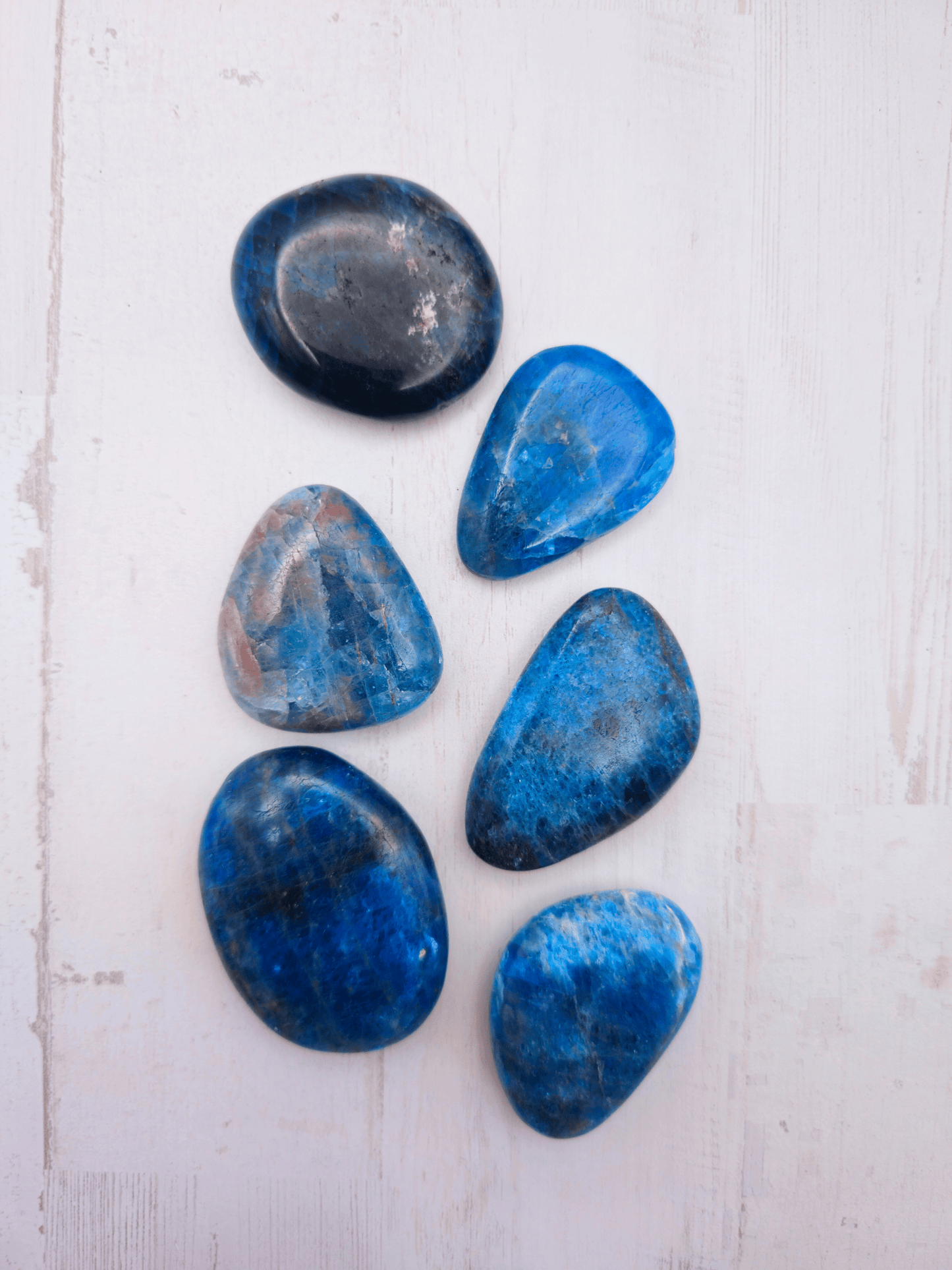 Rodado plano de apatito azul (37–53 mm) en tonos azul, negro y marrón, ideal para claridad, motivación y comunicación equilibrada.