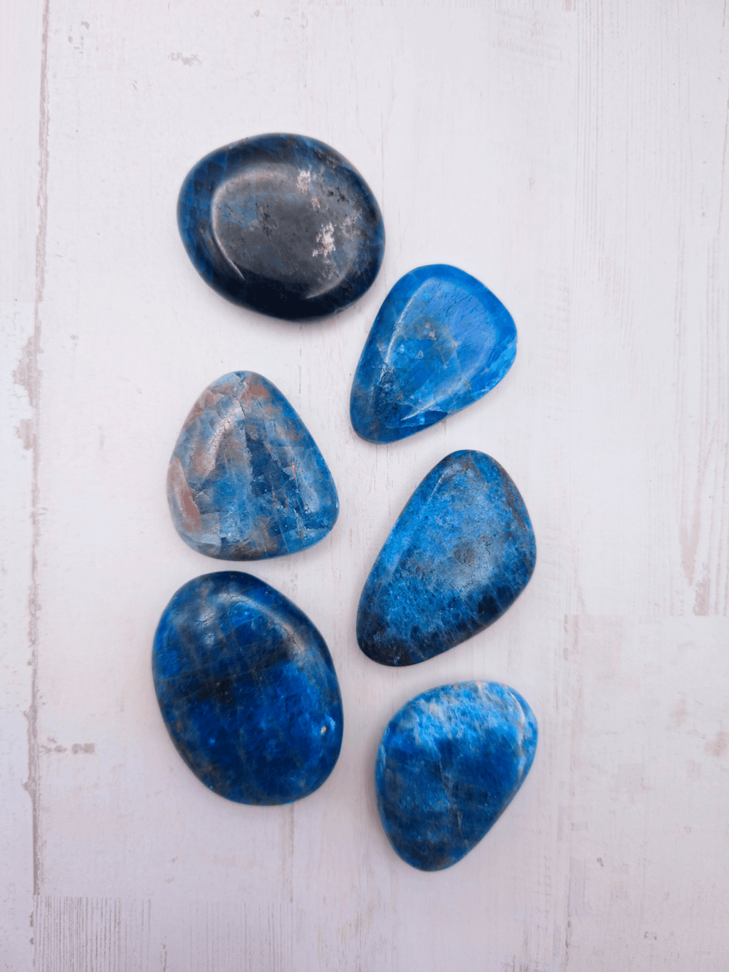 Rodado plano de apatito azul (37–53 mm) en tonos azul, negro y marrón, ideal para claridad, motivación y comunicación equilibrada.
