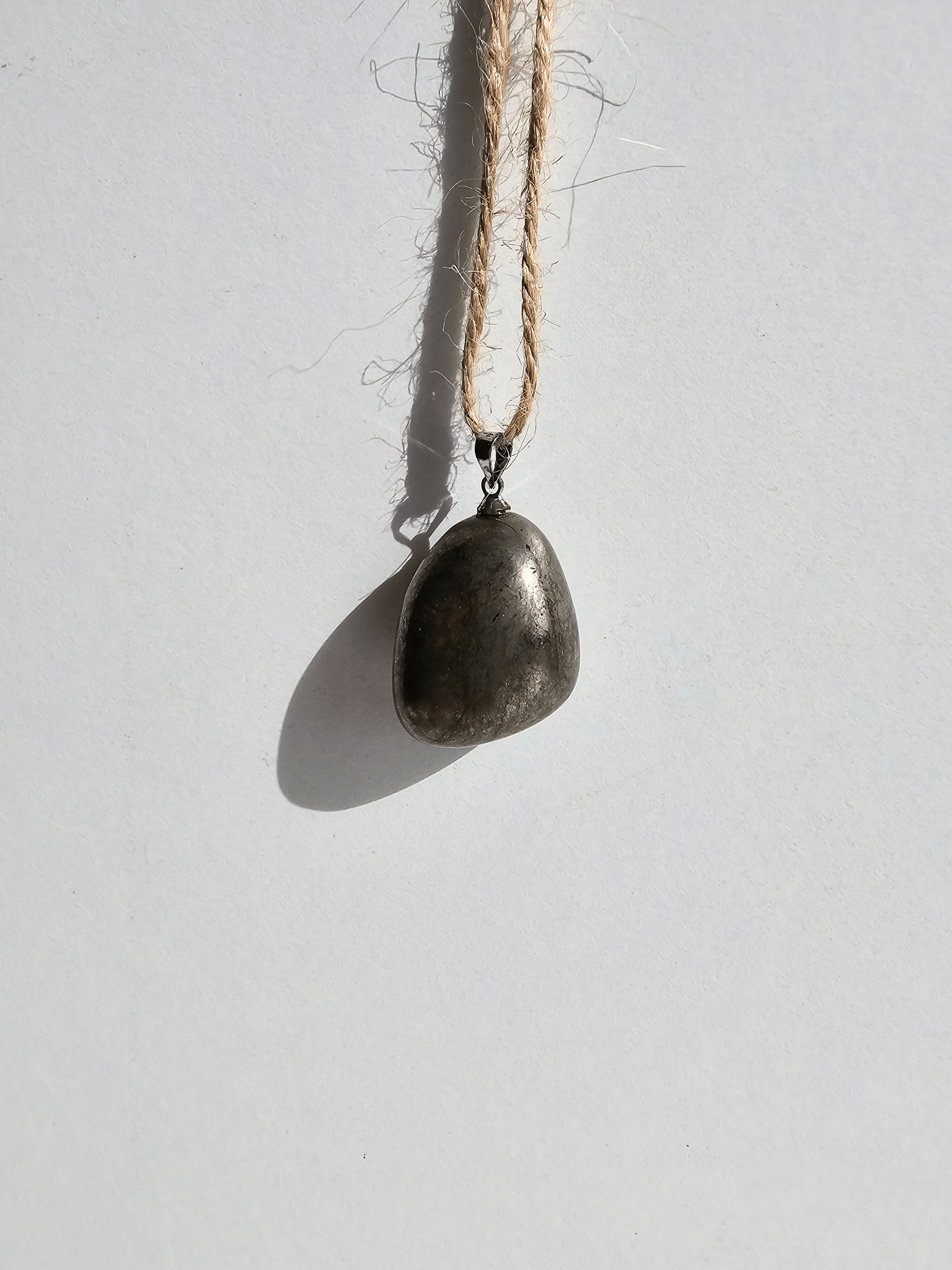Colgante de pirita rodada en tonos dorado y negro, tamaño 20–30 mm, ideal para claridad mental y empoderamiento energético.