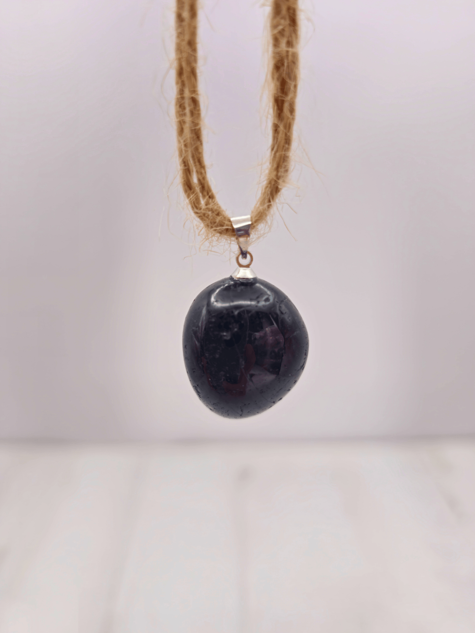 Colgante rodado de turmalina negra (20–30 mm) en tonos negro y marrón, ideal para protección continua y enfoque emocional.