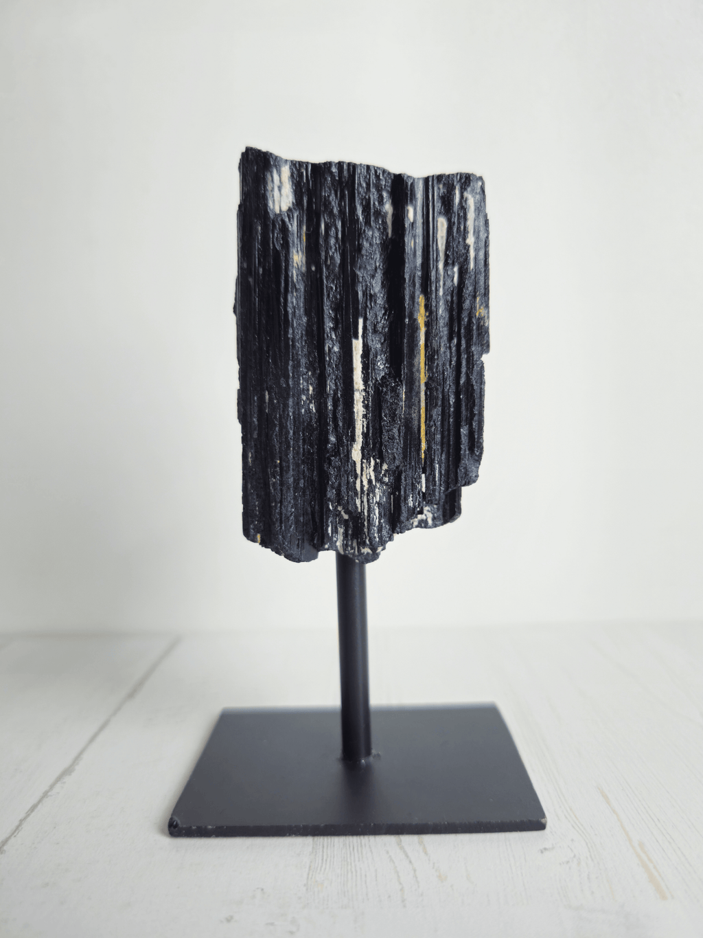 Turmalina negra en bruto con forma tipo catedral sobre base, piedra de protección energética, estabilidad emocional y enraizamiento interior