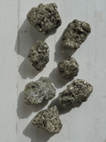 Masivo de pirita entre 70-100 g, tonos dorado y negro, ideal para atraer prosperidad, abundancia y protección energética.