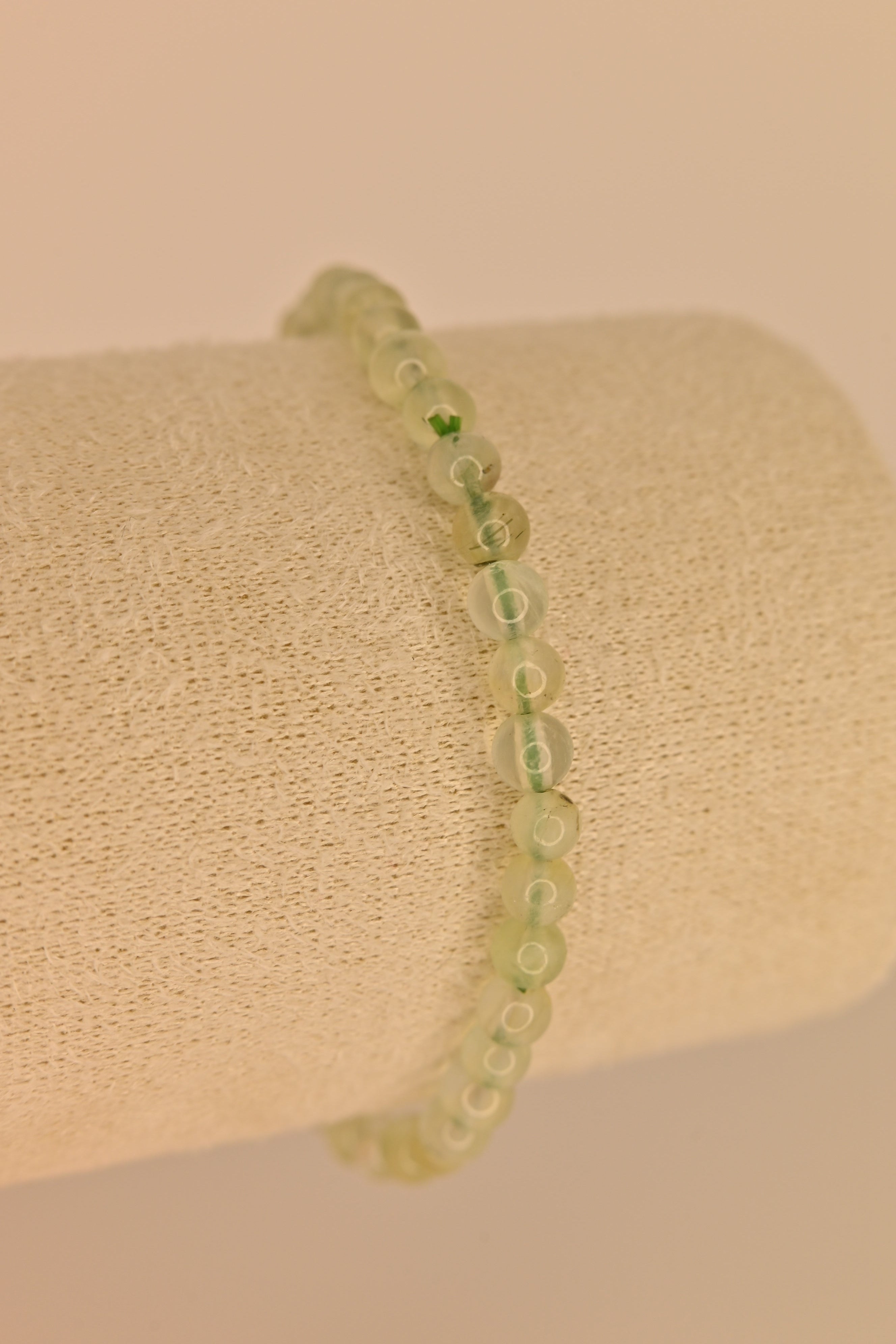 Pulsera de prehnita 4 mm verde translúcida sobre expositor claro para sanación emocional y chakra corazón