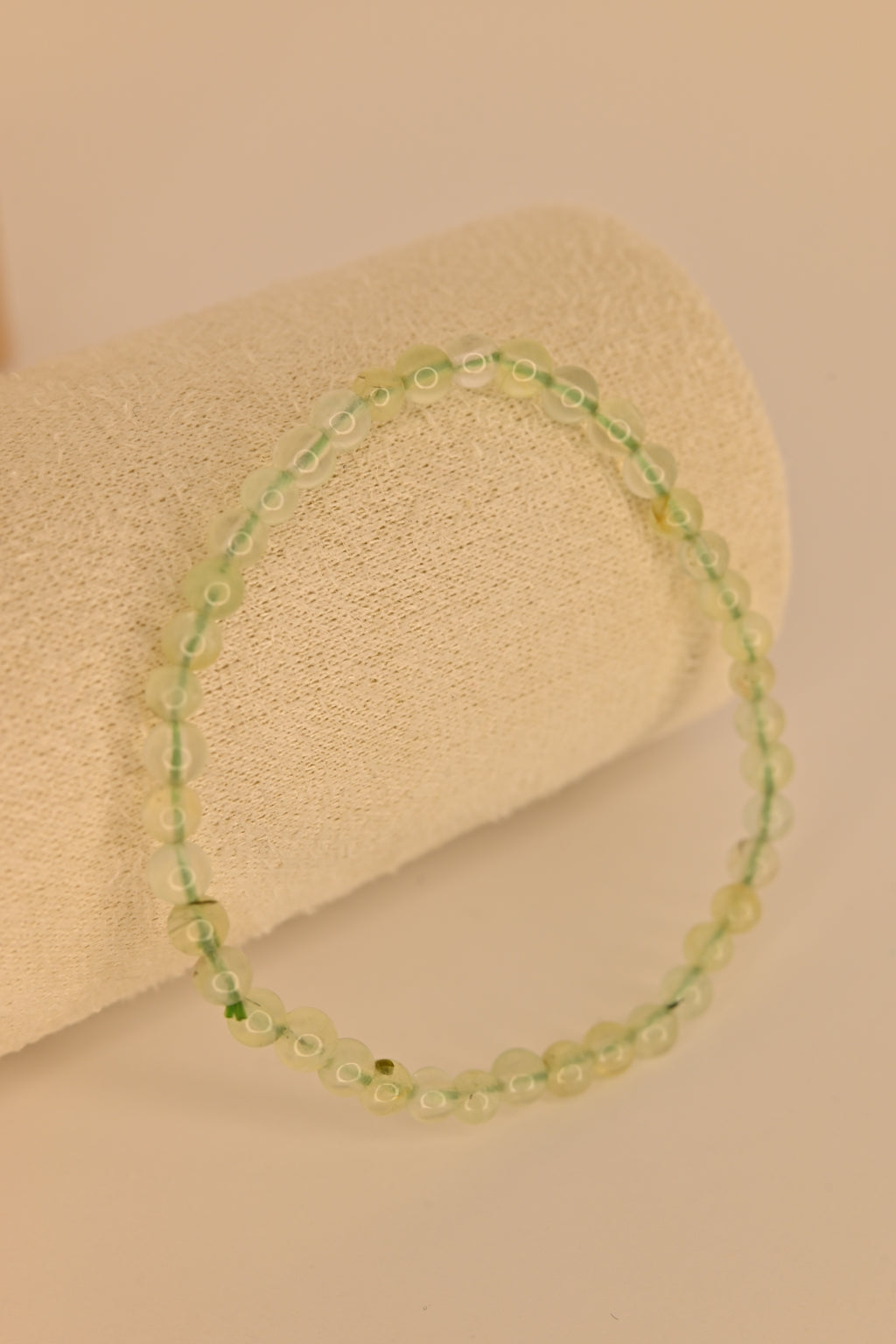 Pulsera de prehnita 4 mm verde translúcida sobre expositor claro para sanación emocional y chakra corazón