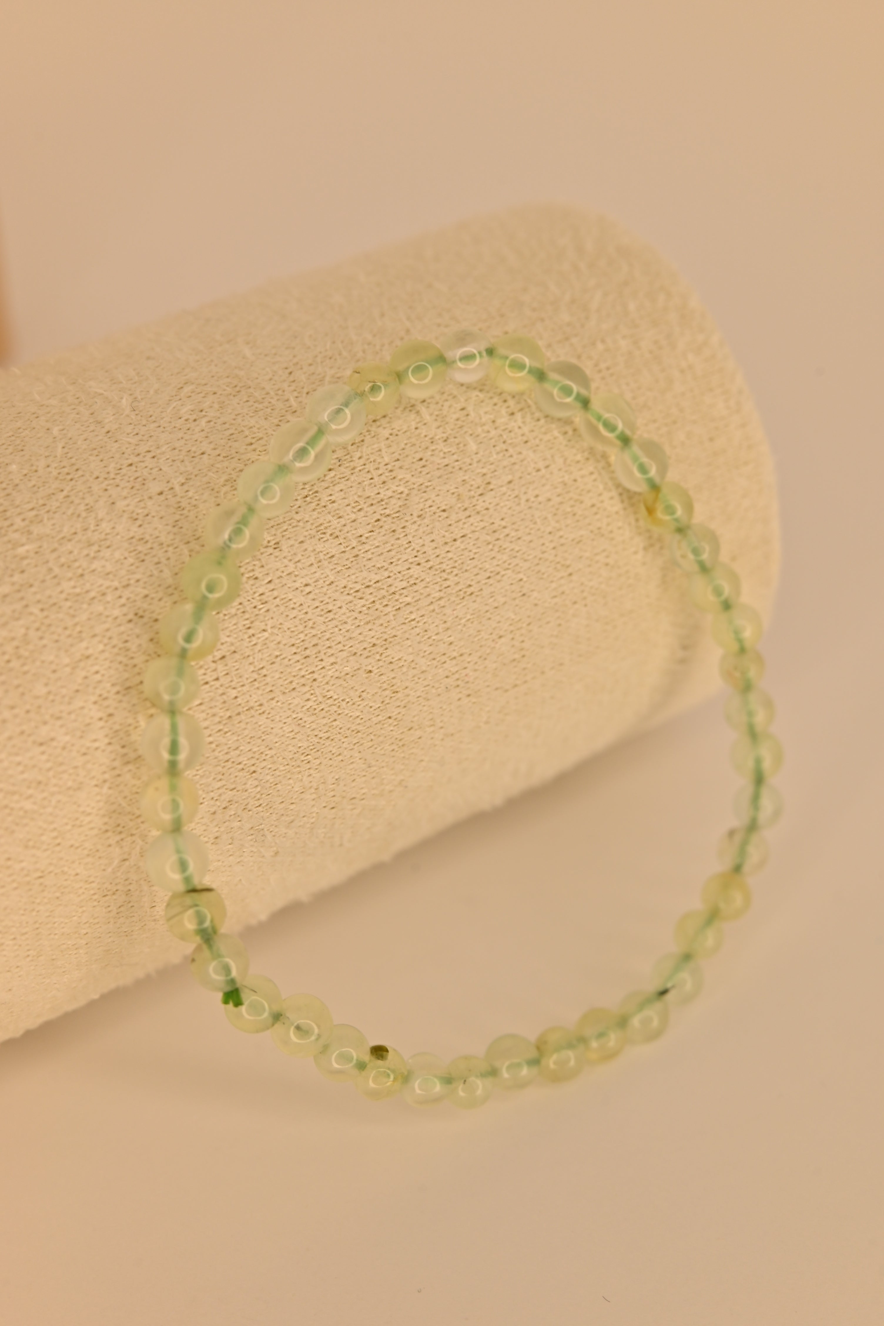 Pulsera de prehnita 4 mm verde translúcida sobre expositor claro para sanación emocional y chakra corazón