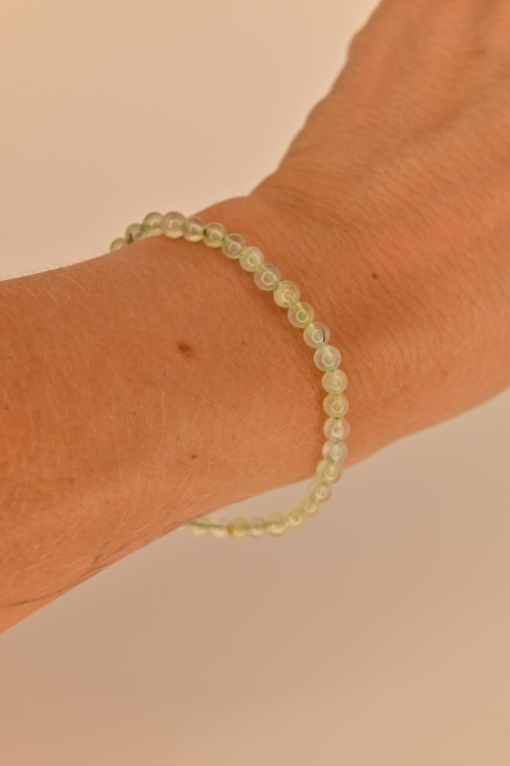 Pulsera de prehnita 4 mm verde translúcida sobre expositor claro para sanación emocional y chakra corazón