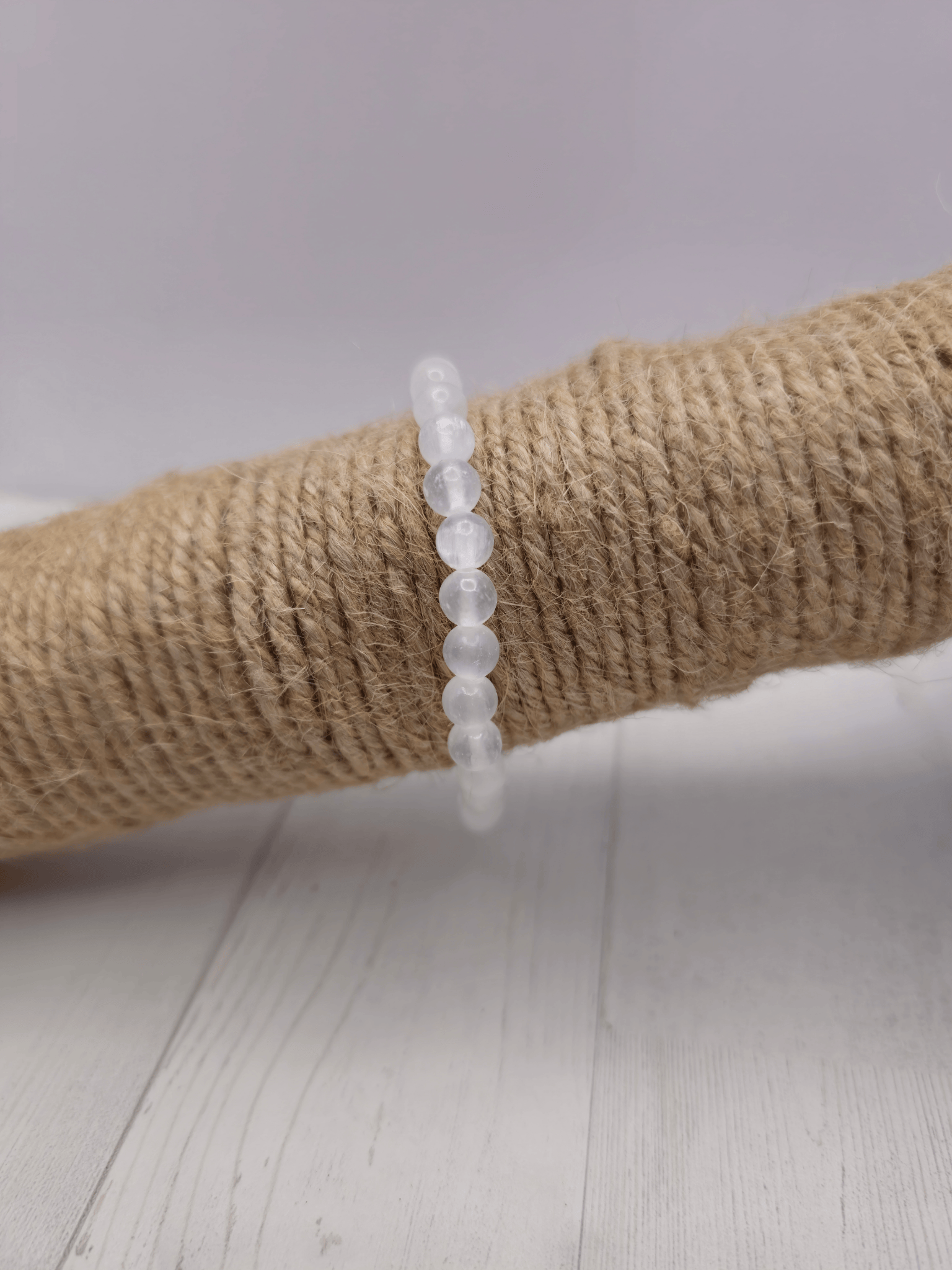 Pulsera de selenita con cuentas de 6 mm en tonos blancos y reflejos perlados, montada en hilo elástico, ideal para claridad mental y elevación energética.