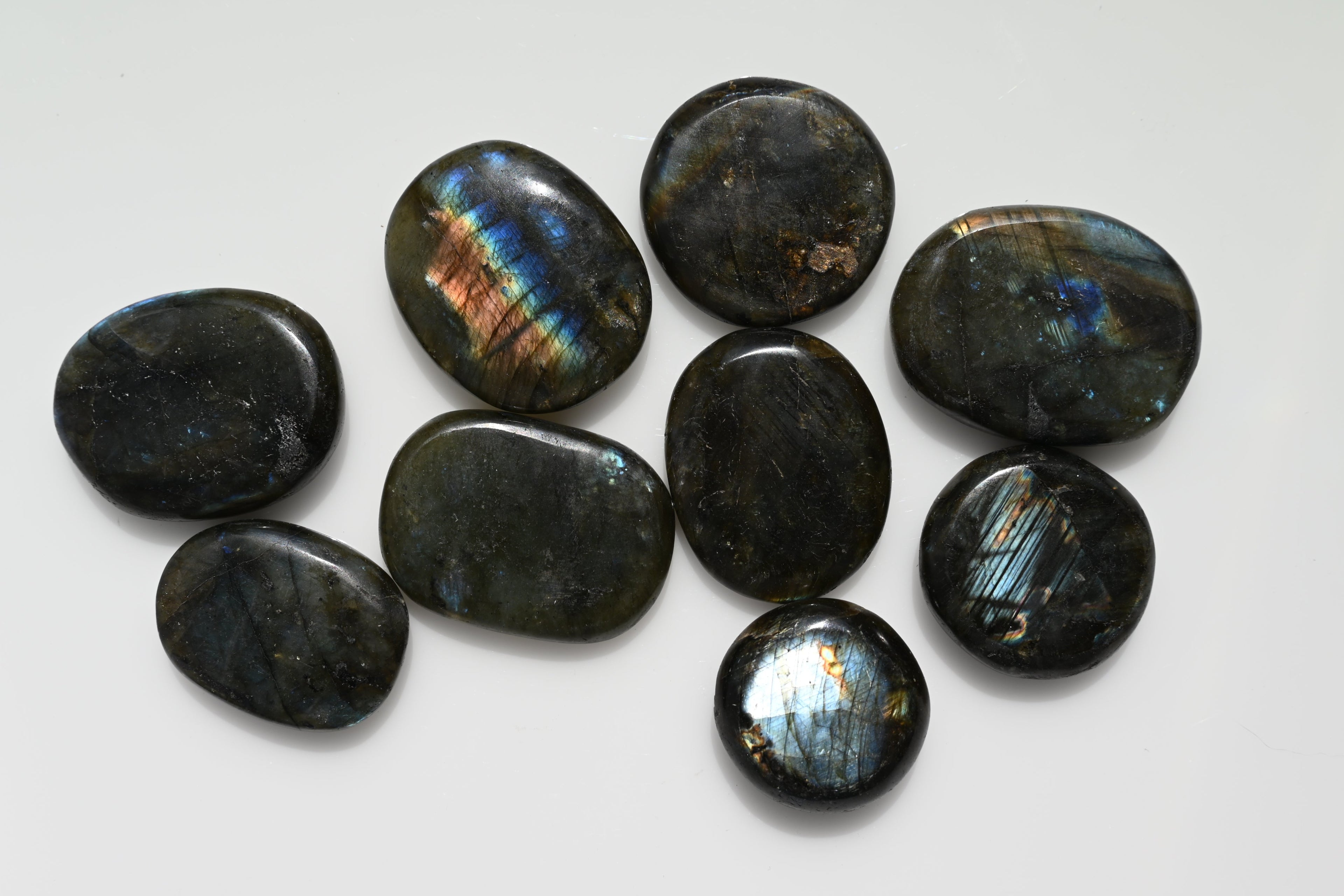 Rodado plano (disco) de labradorita 25–50 mm con iridiscencia azul y anaranjada