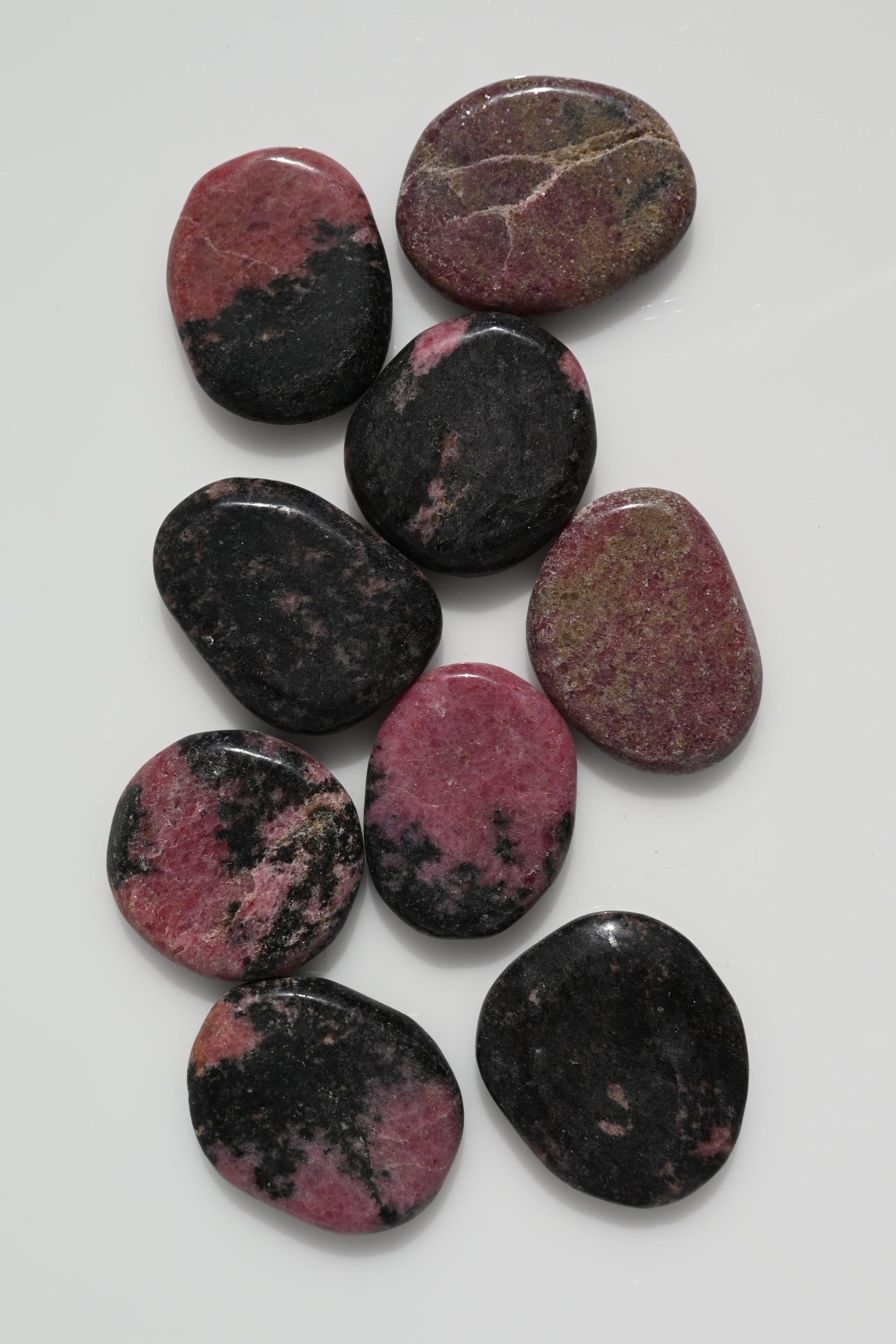 Rodado plano de rodonita rosa con vetas negras 30–50 mm