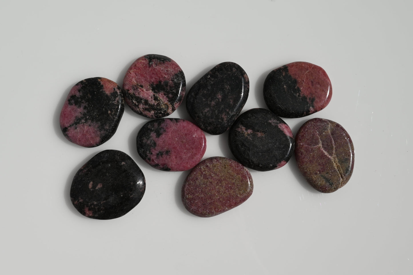 Rodado plano de rodonita rosa con vetas negras 30–50 mm