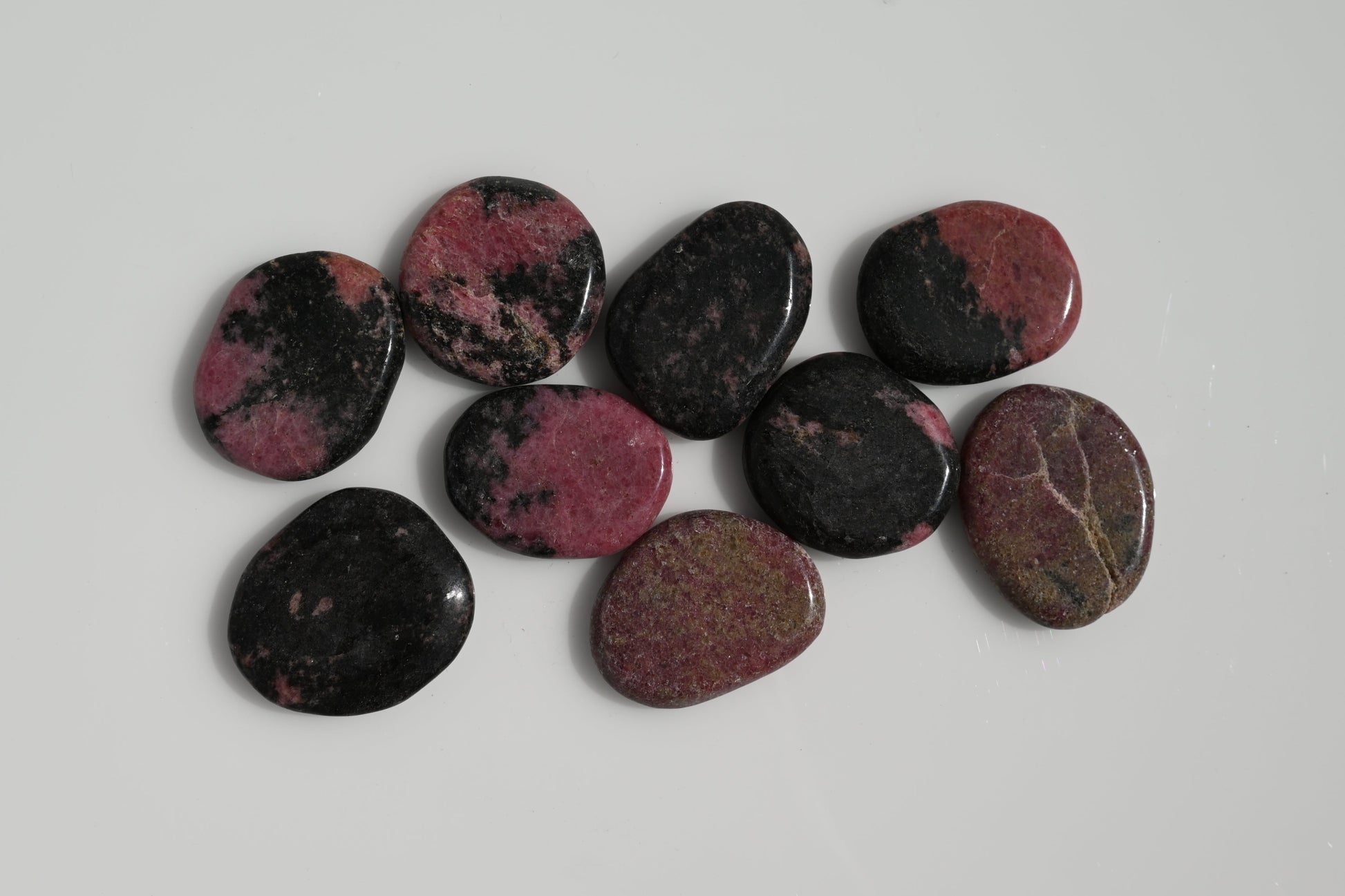 Rodado plano de rodonita rosa con vetas negras 30–50 mm