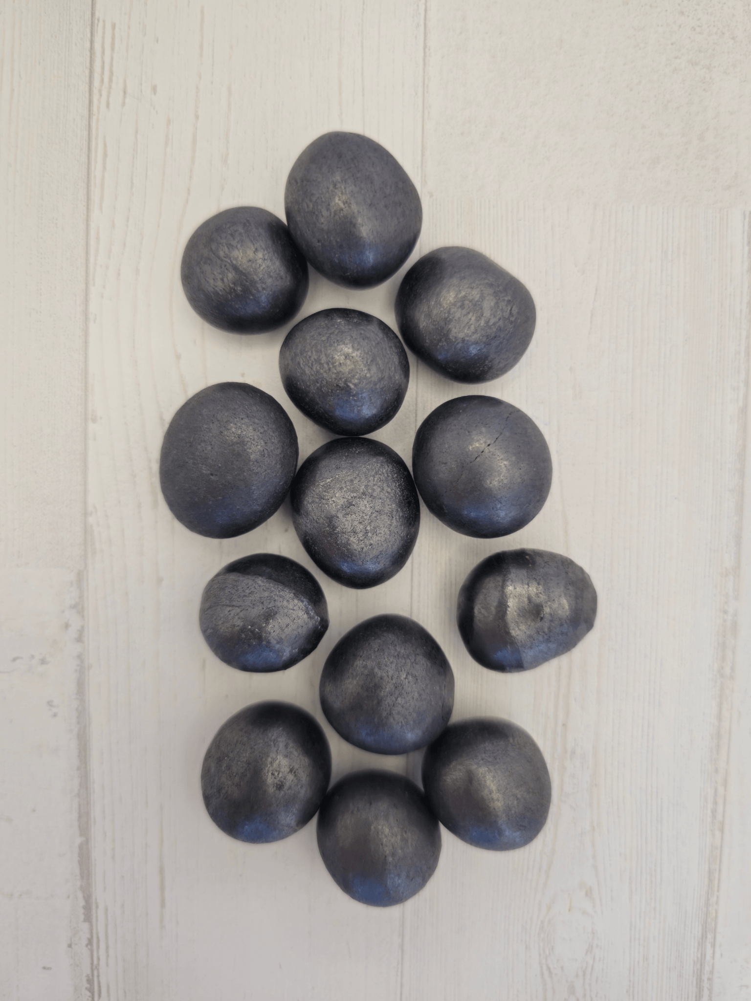 Rodado liso de shungit en tonos gris‑plata, tamaño 16‑21 mm; ideal para conexión a tierra y protección energética.