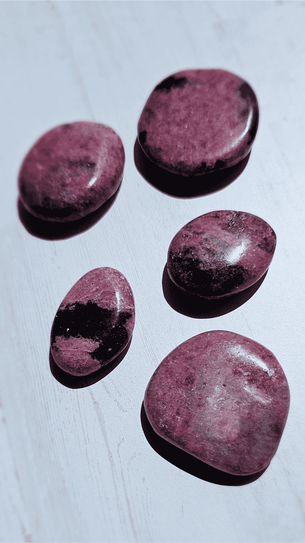 Guijarro plano de rodonita (37–53 mm), en tonos negro, rosa y blanco, ideal para cultivar amor y armonía emocional.